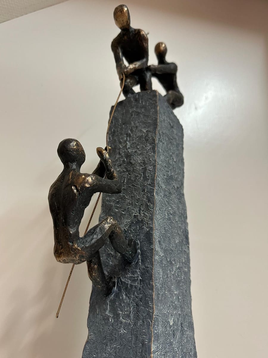 Bronzen beeld van drie figuren die elkaar helpen omhoog te klimmen, symbool voor individuele therapie bij Praktijk Levenswerk in Musselkanaal