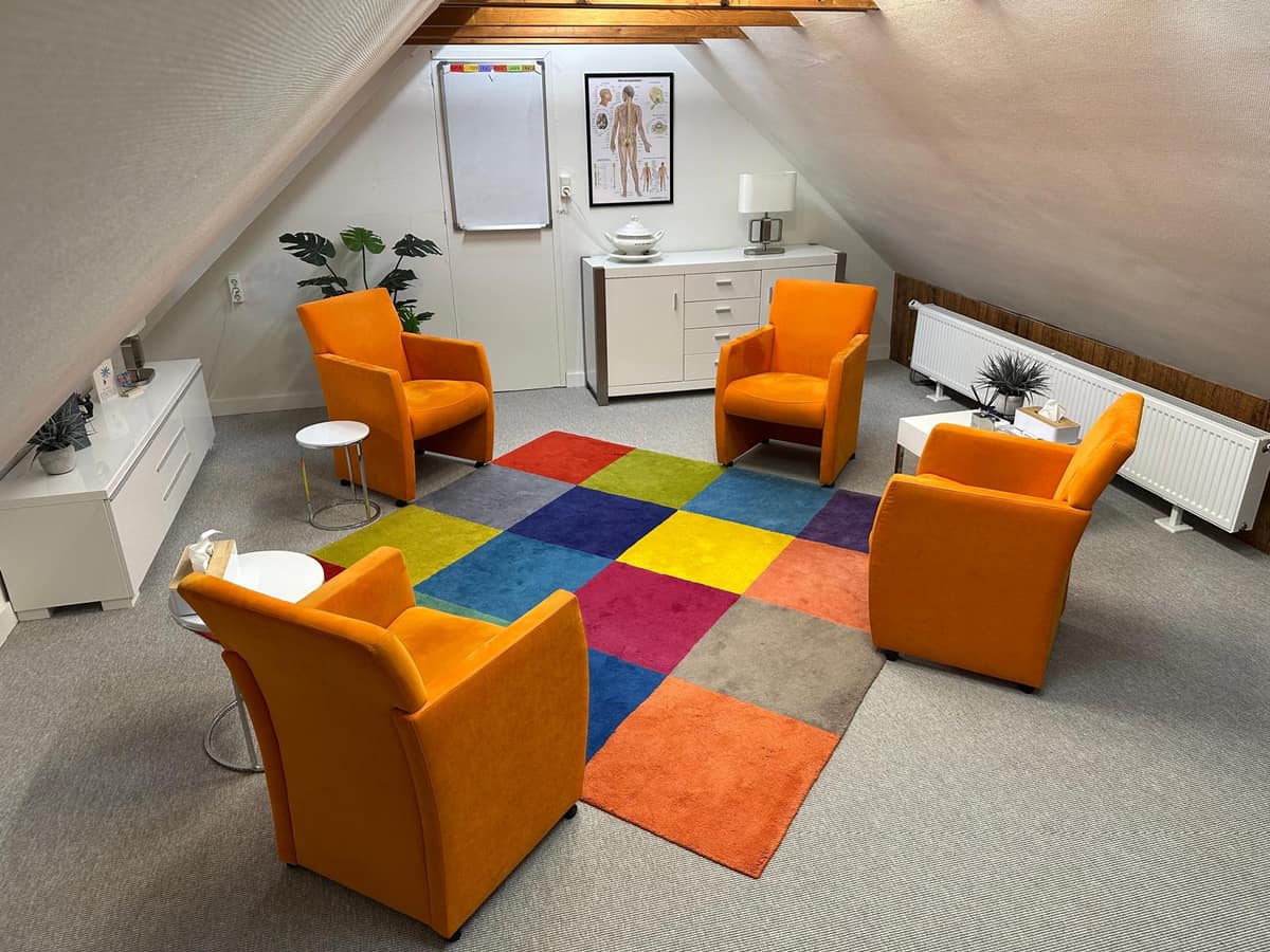 Spreekkamer met warme sfeer en oranje stoelen